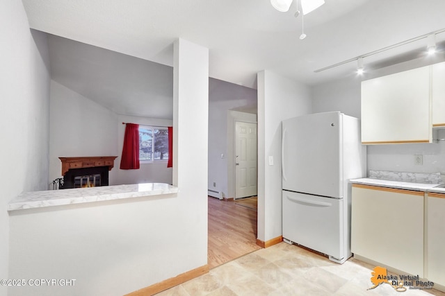 kitchen featuring rail lighting, white cabinets, a baseboard radiator, kitchen peninsula, and white fridge