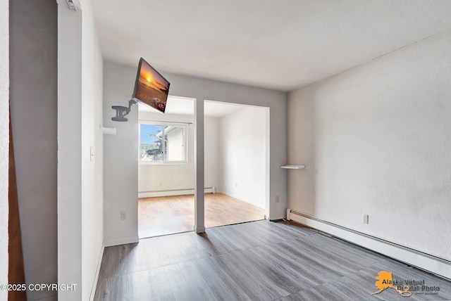 unfurnished bedroom featuring a closet, baseboard heating, and light hardwood / wood-style floors