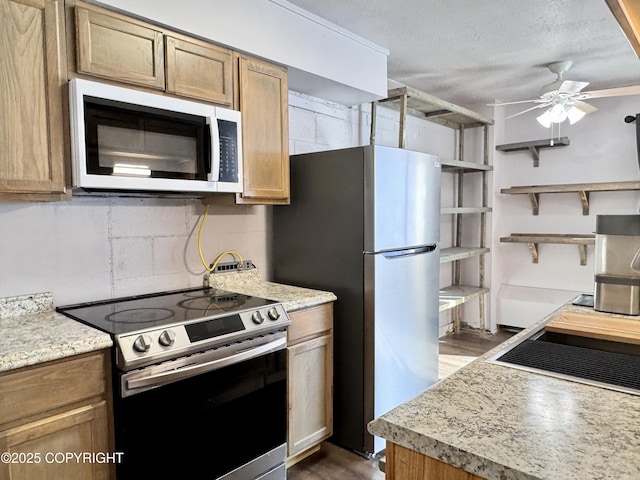 kitchen with open shelves, a textured ceiling, appliances with stainless steel finishes, concrete block wall, and ceiling fan