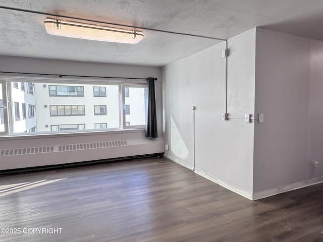 spare room with baseboards, a textured ceiling, wood finished floors, and radiator heating unit