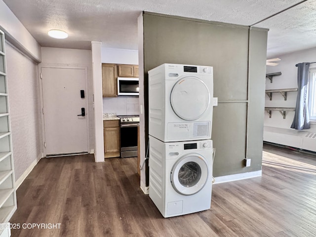 washroom featuring a textured ceiling, dark wood-type flooring, laundry area, and stacked washing maching and dryer