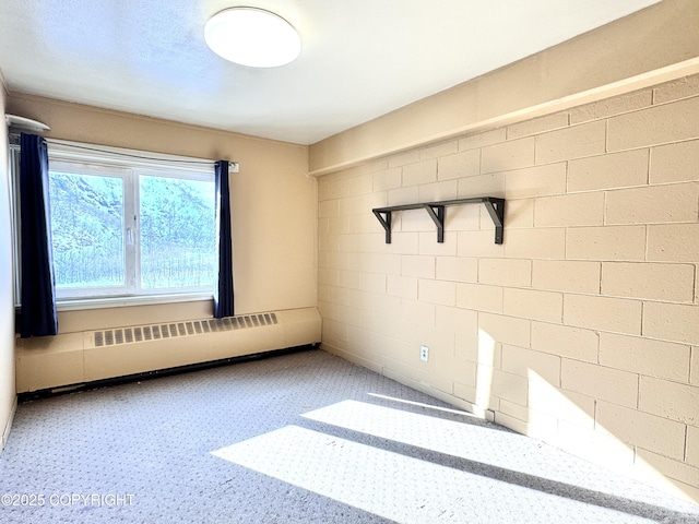 unfurnished room with concrete block wall and radiator heating unit