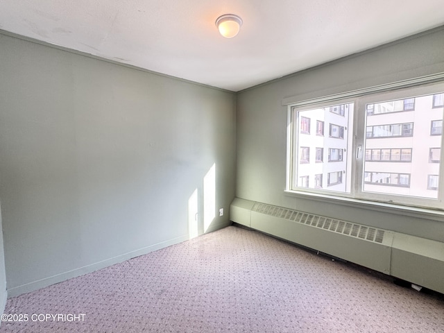 spare room featuring baseboards and a baseboard radiator