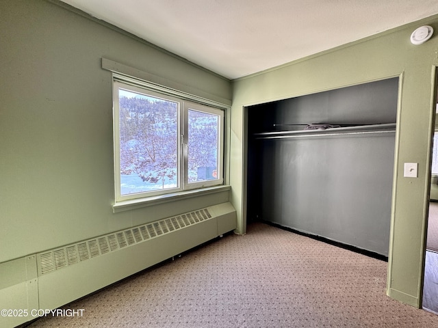 unfurnished bedroom with a baseboard radiator, baseboards, and a closet