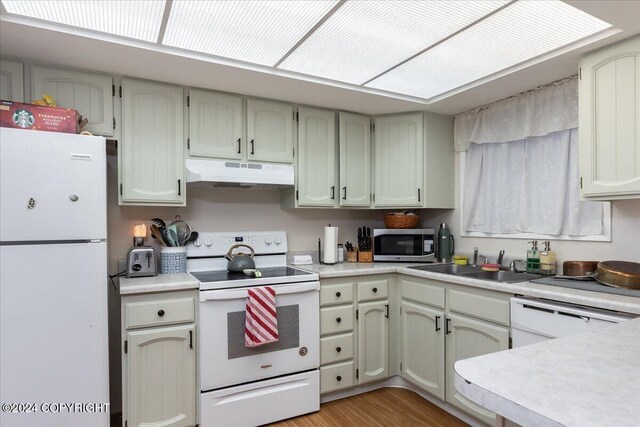 kitchen with light wood-type flooring, white appliances, and sink