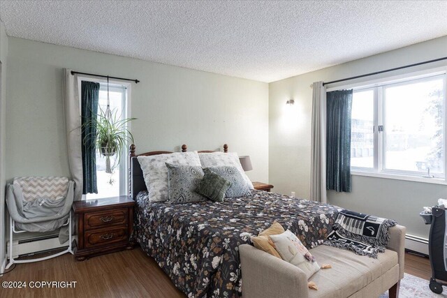 bedroom featuring baseboard heating, hardwood / wood-style floors, and a textured ceiling