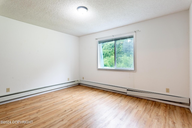 empty room with a textured ceiling and light hardwood / wood-style flooring