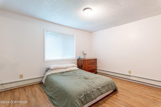 bedroom featuring a textured ceiling, a baseboard radiator, and hardwood / wood-style flooring