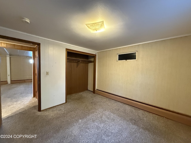 unfurnished bedroom with light carpet, ornamental molding, a closet, and a baseboard heating unit