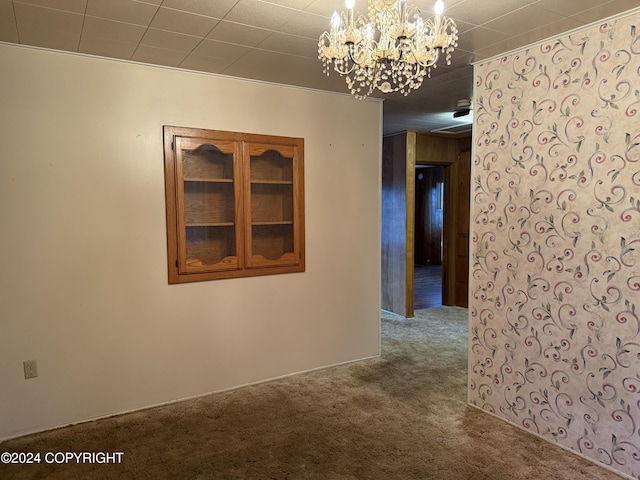 unfurnished room featuring wooden walls, crown molding, carpet, and a chandelier