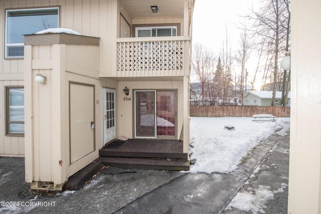 snow covered property entrance with a balcony