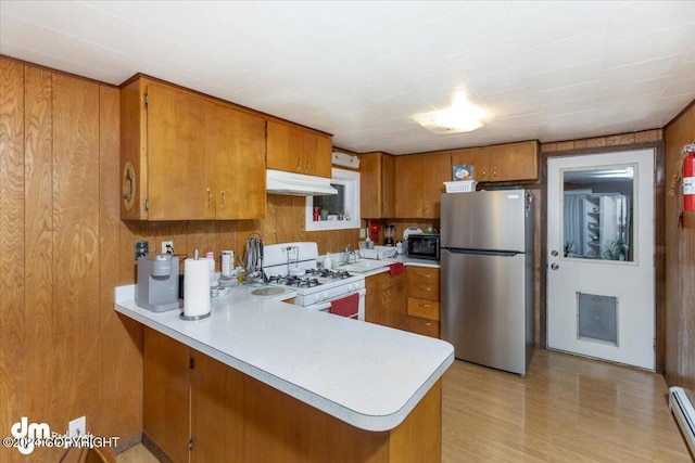 kitchen featuring a baseboard radiator, white range with gas stovetop, stainless steel refrigerator, and kitchen peninsula