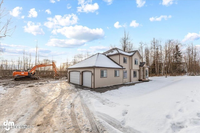 snow covered property with a garage