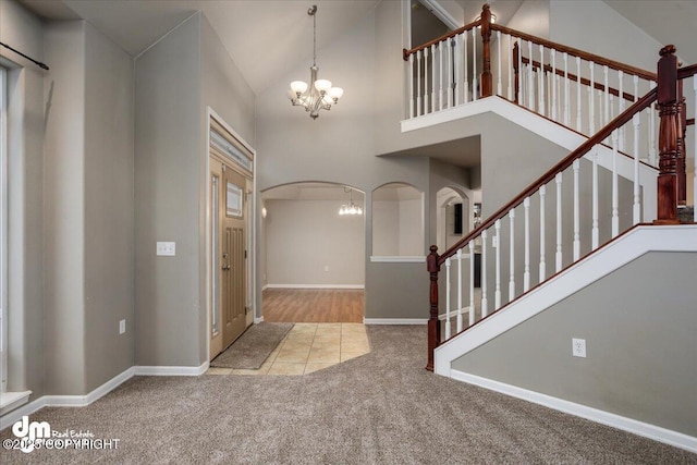 carpeted entryway with high vaulted ceiling and a notable chandelier