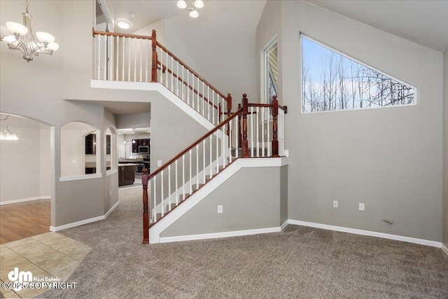 stairway featuring an inviting chandelier, carpet flooring, and a high ceiling