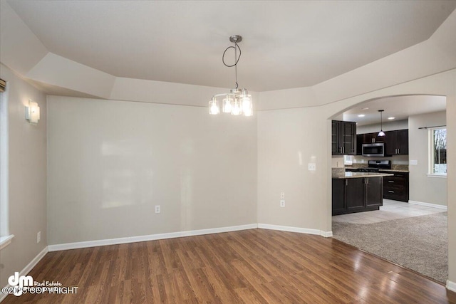 unfurnished dining area with an inviting chandelier and light hardwood / wood-style flooring