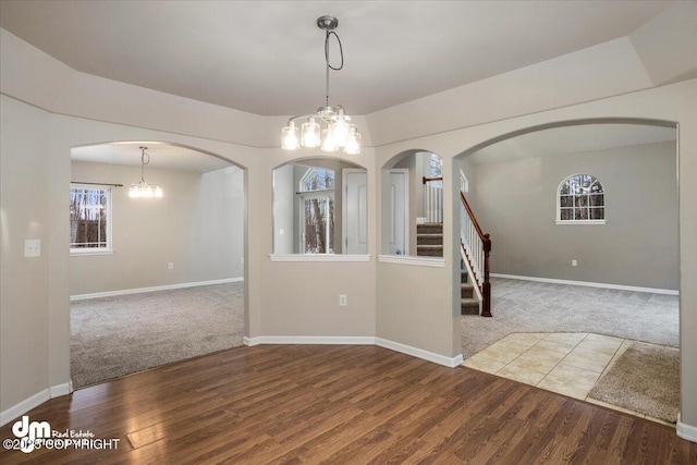 spare room featuring wood-type flooring and a notable chandelier