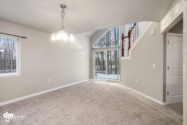 carpeted empty room featuring vaulted ceiling and an inviting chandelier