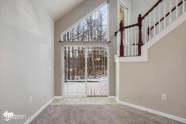 carpeted foyer featuring a towering ceiling