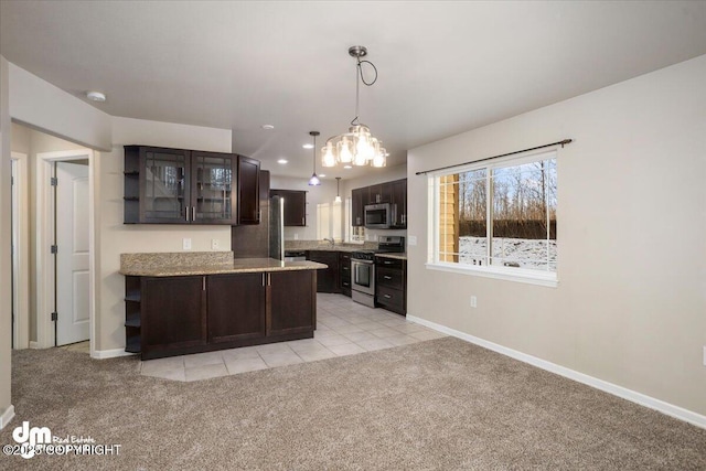 kitchen featuring appliances with stainless steel finishes, light colored carpet, dark brown cabinetry, and decorative light fixtures