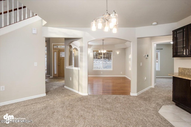 unfurnished dining area with a notable chandelier and light colored carpet