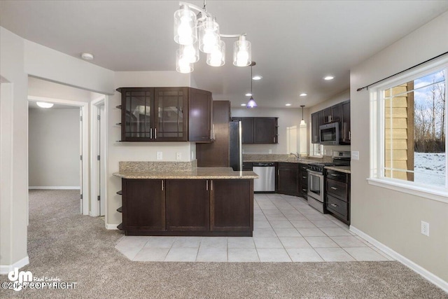 kitchen featuring appliances with stainless steel finishes, dark brown cabinets, light carpet, and pendant lighting