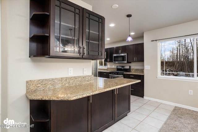 kitchen featuring hanging light fixtures, light tile patterned floors, light stone counters, stainless steel appliances, and dark brown cabinets