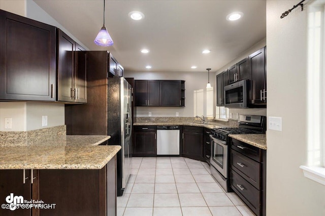 kitchen with stainless steel appliances, dark brown cabinetry, light stone counters, and decorative light fixtures