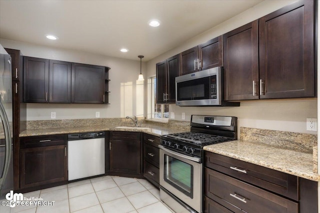 kitchen with pendant lighting, stainless steel appliances, sink, and light stone counters