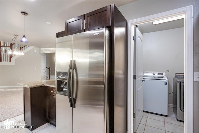 kitchen featuring decorative light fixtures, light tile patterned floors, stainless steel refrigerator with ice dispenser, light stone countertops, and washing machine and dryer