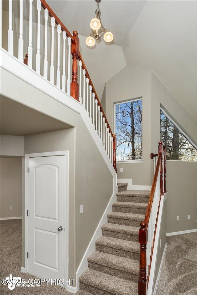 staircase with an inviting chandelier, lofted ceiling, and carpet flooring