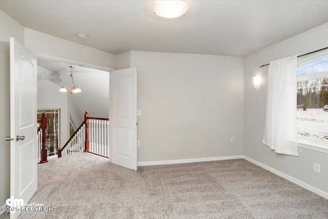 carpeted empty room featuring an inviting chandelier