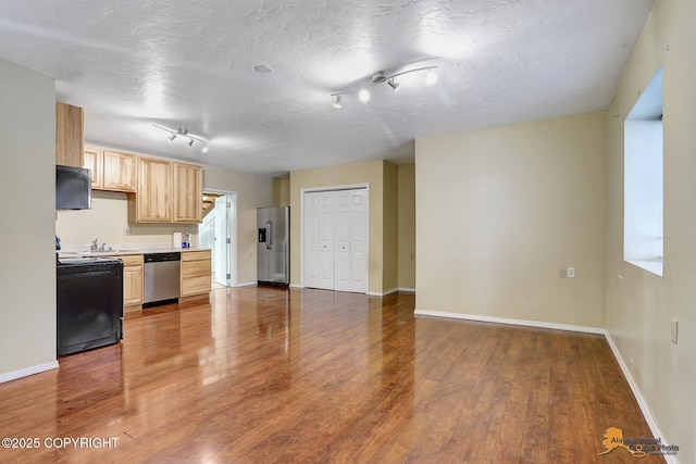 kitchen featuring stainless steel appliances, hardwood / wood-style floors, a textured ceiling, and light brown cabinets