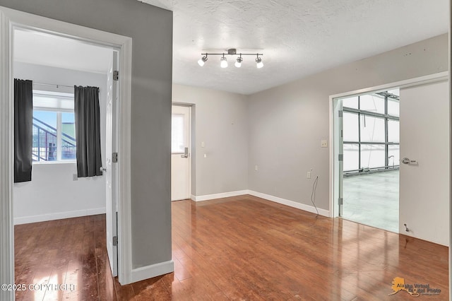 unfurnished room with dark hardwood / wood-style flooring and a textured ceiling