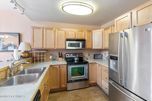 kitchen featuring a textured ceiling, light brown cabinetry, sink, and appliances with stainless steel finishes