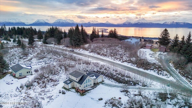 snowy aerial view with a water and mountain view