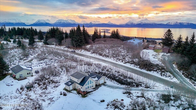 snowy aerial view featuring a water and mountain view