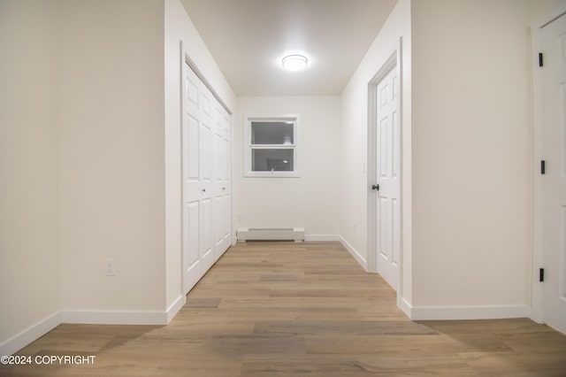 hallway with light hardwood / wood-style floors and a baseboard radiator