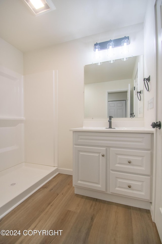 bathroom with wood-type flooring, vanity, and walk in shower