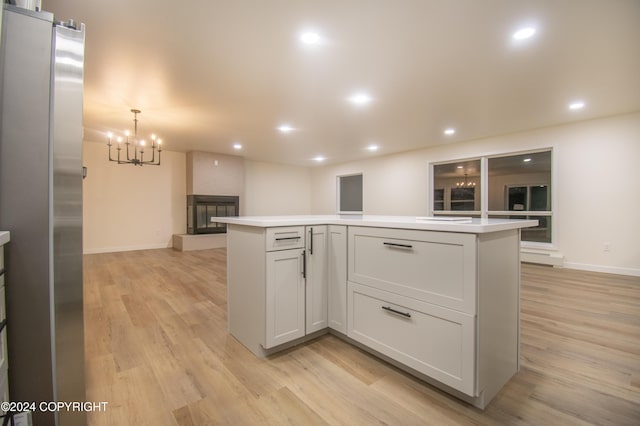 kitchen with white cabinetry, light hardwood / wood-style flooring, stainless steel fridge, pendant lighting, and a kitchen island