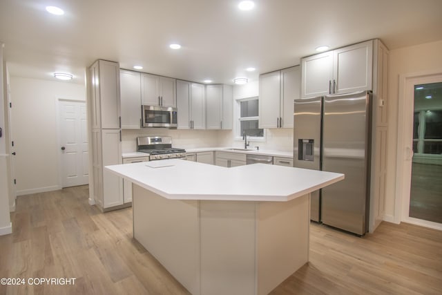 kitchen featuring white cabinetry, sink, a center island, light hardwood / wood-style floors, and appliances with stainless steel finishes