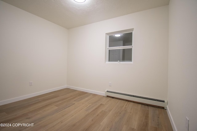 unfurnished room featuring light wood-type flooring, a textured ceiling, and a baseboard heating unit