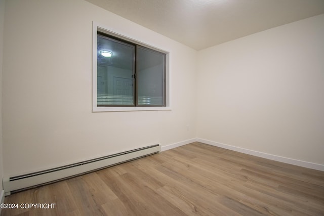 unfurnished room featuring light hardwood / wood-style floors and baseboard heating