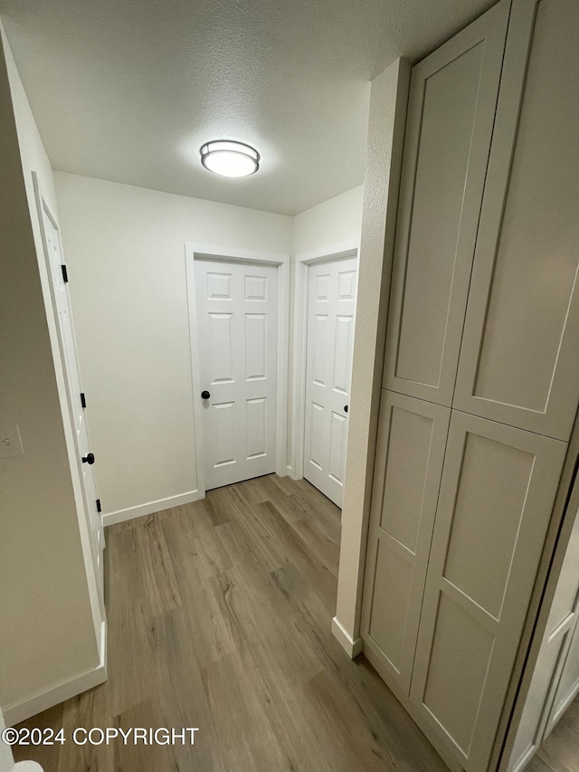 hall with light hardwood / wood-style flooring and a textured ceiling