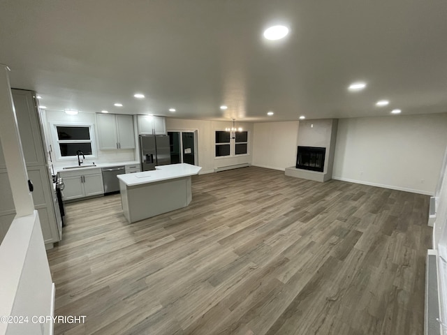 kitchen with a large fireplace, stainless steel appliances, a kitchen island, and light hardwood / wood-style flooring