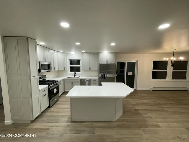 kitchen featuring a center island, stainless steel appliances, a baseboard heating unit, a notable chandelier, and pendant lighting