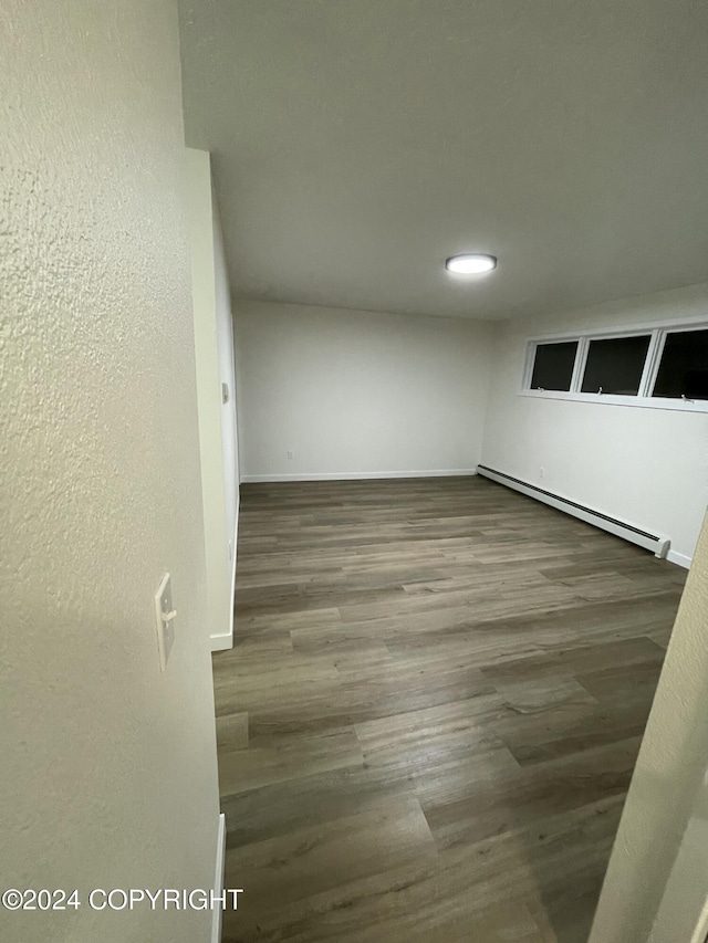 unfurnished room featuring hardwood / wood-style flooring and a baseboard heating unit