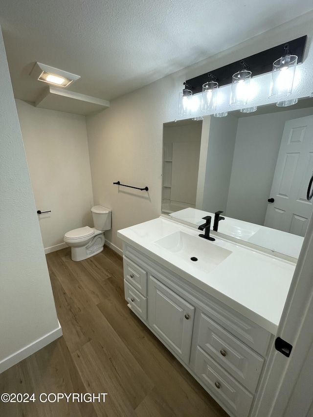 bathroom with a textured ceiling, vanity, hardwood / wood-style flooring, and toilet