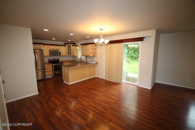 kitchen featuring sink, dark hardwood / wood-style floors, decorative light fixtures, kitchen peninsula, and stainless steel appliances