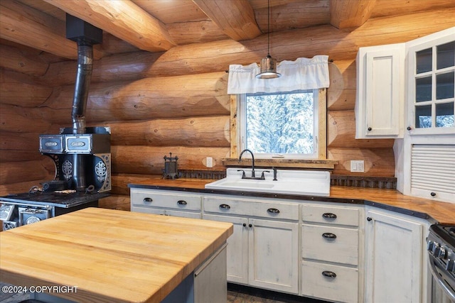 kitchen featuring white cabinets, hanging light fixtures, log walls, beamed ceiling, and butcher block counters